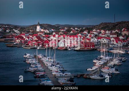 Red houses with church and boats in the harbor in the village of Skärhamn on the archipelago island of Tjörn on the west coast of Sweden, in the evening Stock Photo