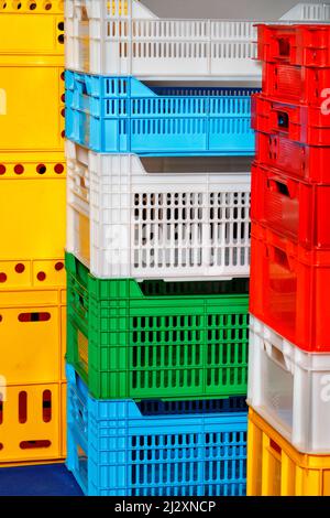 Multi colored plastic cargo crates stacked up on top of each other. Vertical image. Stock Photo