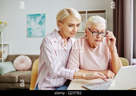 Portrait of young woman teaching senior mother using laptop and internet at home Stock Photo