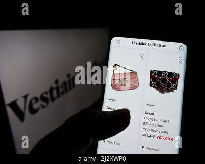 Person holding cellphone with webpage of French e-commerce company Vestiaire Collective SA on screen with logo. Focus on center of phone display. Stock Photo