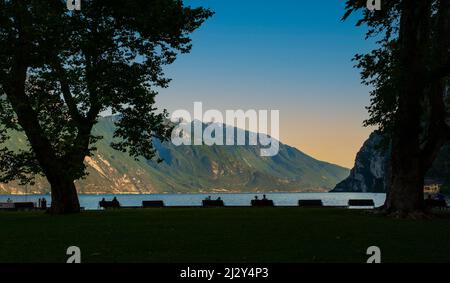 People waiting for the sunset on the shore of Lake Garda, in Riva del Garda. Trento. Italy Stock Photo