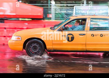 NEW YORK CITY, NY/USA - OCTOBER 22TH, 2014: A taxi cab splashes in a rain pond, at Times Square area, October 22nd, 2014, New York City, NY, USA. Stock Photo