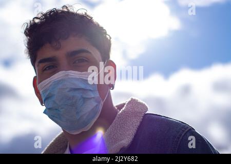 A selfie of a Latino man wearing a face mask to be protected from influenza or COVID-19. Stock Photo