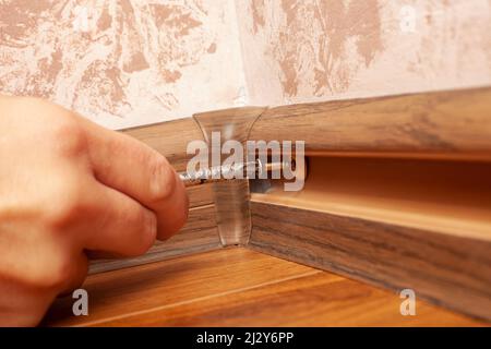 installation of plastic skirting boards, screwing the plinth. Stock Photo