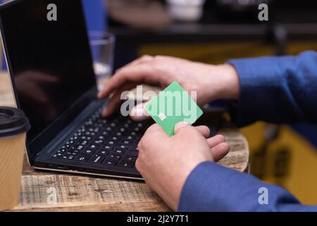 Man's hand using credit card along with his laptop Stock Photo