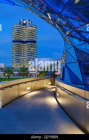 Blue illuminated BMW Welt building with BMW four-cylinder and BMW Museum in the background, Munich, Upper Bavaria, Bavaria, Germany Stock Photo