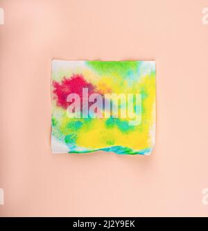 White paper napkin with multi-colored paint spots. Abstract background, copy space. Stock Photo