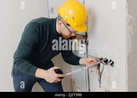 Man foreman builder check checking electrical panel and work of electrician in apartment. Stock Photo