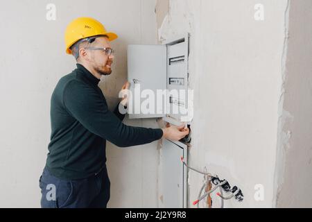 Man foreman builder check checking electrical panel and work of electrician in apartment. Stock Photo