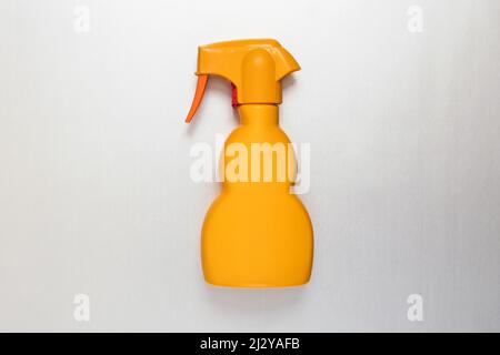 Generic unlabelled yellow plastic spray bottle lying flat on white in a concept of retail packaging and household hygiene with copyspace Stock Photo