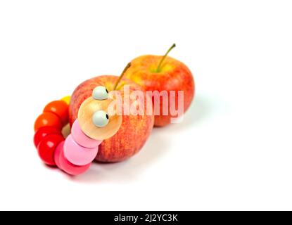 Toy worm in front of apples on a white background Stock Photo