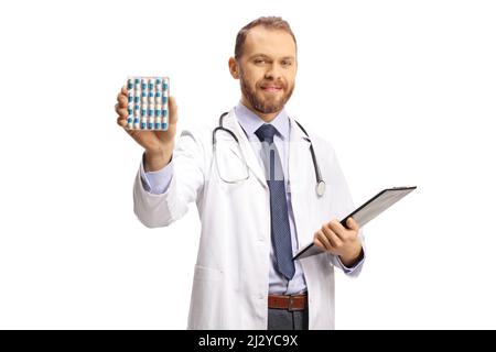 Young male doctor holding a pack of pills isolated on white background Stock Photo