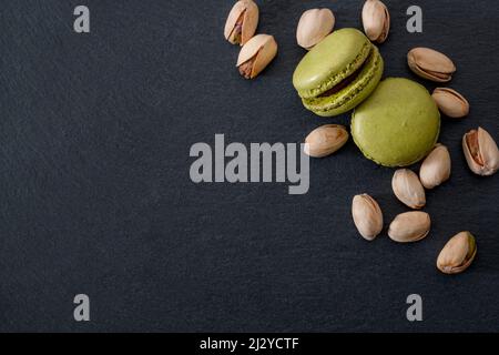 French dessert, sweet meringue based confectionery and expensive sweets concept with green pistachio flavored macaroon or macaron with a bunch of pist Stock Photo