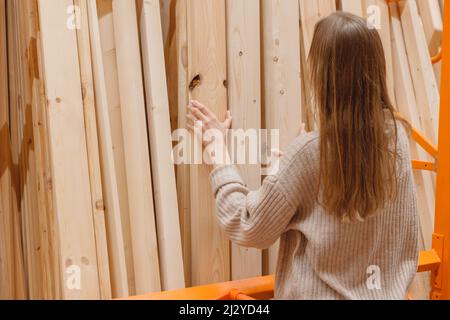 Woman choosing wooden plank in hardware store. Building materials for home renovation Stock Photo