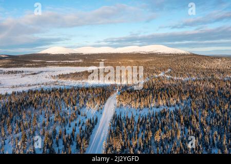 Snow-covered country road, behind it the Pallastunturi, Muonio, Lapland, Finland Stock Photo