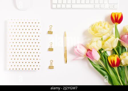 Festive spring composition: tulips, a notebook with a pen, on a white background. the concept of spring holidays of a freelancer or blogger Stock Photo