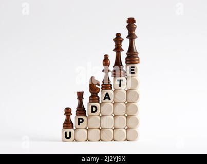 Chess pieces on the ladder of wooden cubes with the word update. Updating concept. Stock Photo