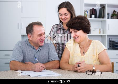Cheerful senior man and woman signing documents Stock Photo