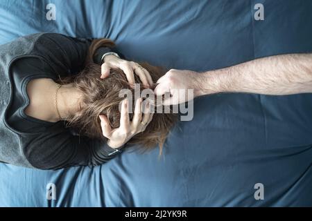 Man assaulting his wife in the home, scene of gender violence against women. Stock Photo