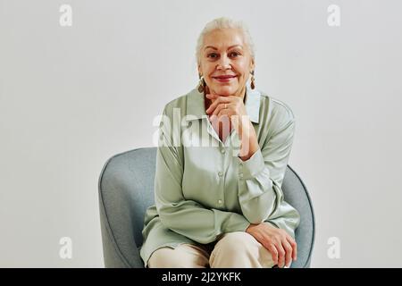 Minimal portrait of elegant senior woman looking at camera and smiling while posing in studio, copy space Stock Photo