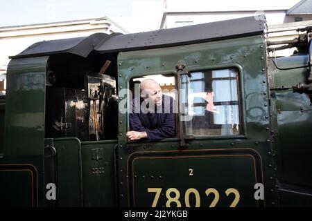 Steam train engine driver looking out of the cab on British locomotive 78022 BR Standard Class 2MT 2-6-0 at Oxenhope Station at Worth Valley Railway Stock Photo