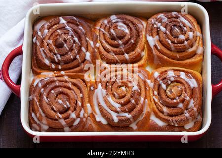 Traditional cinnamon buns with icing on a wooden table. Rustic style. Stock Photo