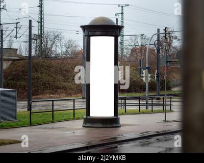Advertising pillar in the city. Blank mockup for testing ad designs on the column next to the street. Billboard template with a white rectangle. Stock Photo