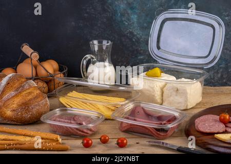 Transparent Plastic container with oriental honey sweets & cake with milk on a wooden table & black background, Black Plastic plate Stock Photo
