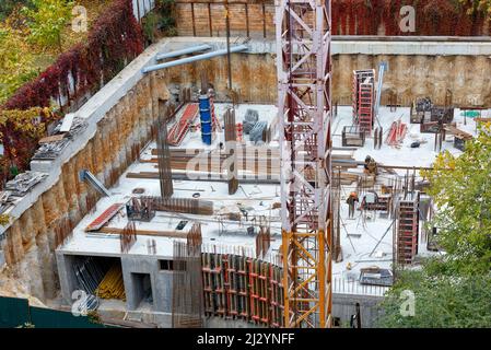 A fragment of the construction site of the foundation of a new building with a tower crane, metal reinforcement and concrete pouring. View from above. Stock Photo