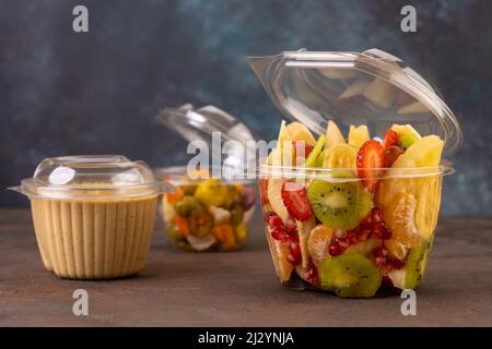 Transparent Plastic container with oriental honey sweets & cake with milk on a wooden table & black background, Black Plastic plate Stock Photo