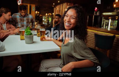 African american female laughing while enjoying drinks with friends  Stock Photo