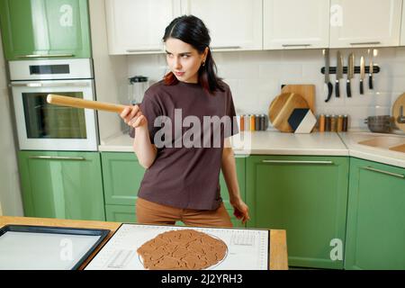 Young happy joyful brunette mixed race woman cooking christmas homemade cookies. Stock Photo