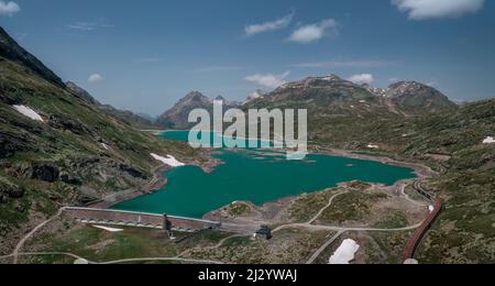 Dam of the Lago Bianco reservoir at the Bernina Pass in the sun from above Stock Photo