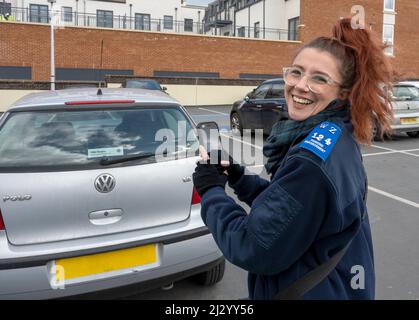 Happy at work, a parking enforcement officer at work in a car park, Farnham, Surrey, England, UK. Stock Photo