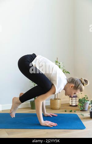caucasian woman is doing Bakasana Stock Photo