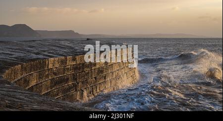 Waves created by Storm Barra crashing against The Cobb at Lyme Regis in Dorset, England, UK, just after sunrise the day after the main storm Stock Photo