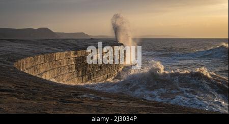 Waves created by Storm Barra crashing against The Cobb at Lyme Regis in Dorset, England, UK, just after sunrise the day after the main storm Stock Photo