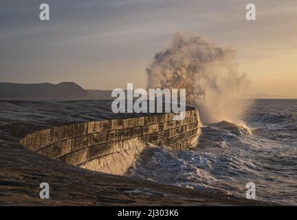 Waves created by Storm Barra crashing against The Cobb at Lyme Regis in Dorset, England, UK, just after sunrise the day after the main storm Stock Photo