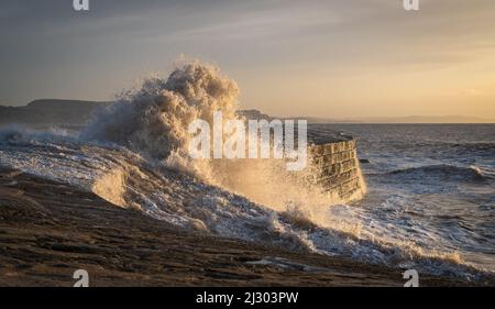 Waves created by Storm Barra crashing against The Cobb at Lyme Regis in Dorset, England, UK, just after sunrise the day after the main storm Stock Photo