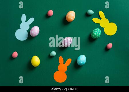 Beautiful different colorful Easter eggs with bunnies of paper on green Stock Photo