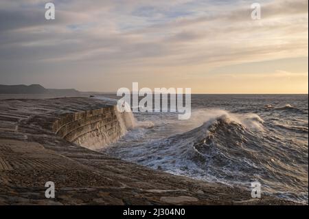 Waves created by Storm Barra crashing against The Cobb at Lyme Regis in Dorset, England, UK, just after sunrise the day after the main storm Stock Photo