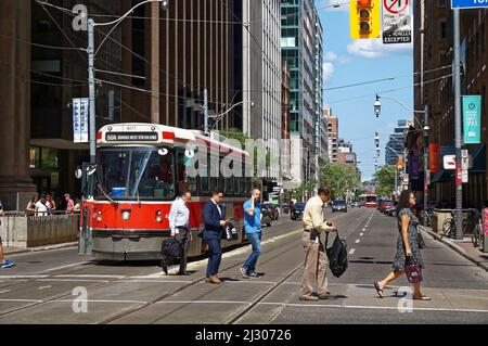 Toronto, Canada - 06 27 2016: City dwellers crossing the street in front of an old streetcar on King at Yonge st. intersection. Stock Photo