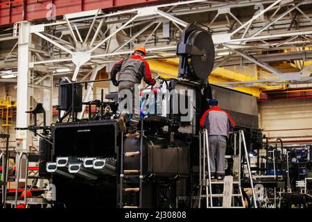 Industrial workers assembles agricultural harvester in workshop Stock Photo
