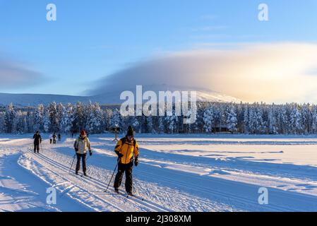 Cross-country skiers on frozen lake at Aekaeslampolo,, Aekaeslampolo, Finland Stock Photo