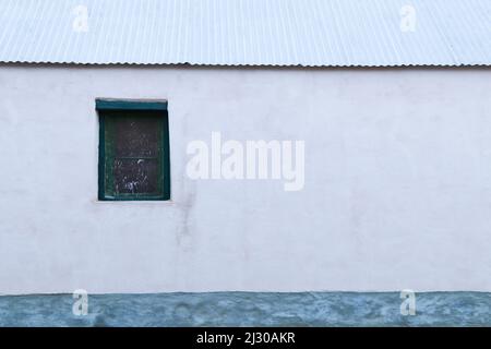Plastered White Farmhouse Wall With Window And Sheet Roof Stock Photo