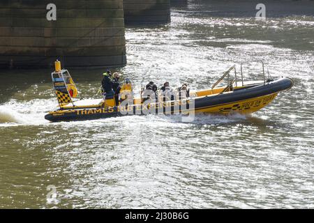 A yellow sightseeing speedboat by the Thames Rib Experience speeding down the River Thames on a sunny day. London - 12th March 2022 Stock Photo