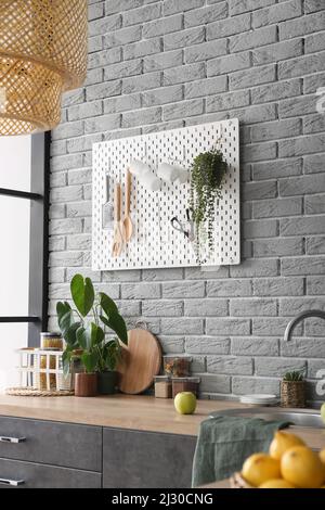 Stylish counter and pegboard on grey brick wall in modern kitchen Stock ...