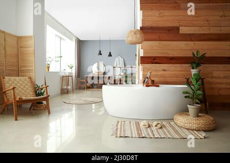 Interior of modern bathroom with white bathtub, sink and houseplants Stock Photo