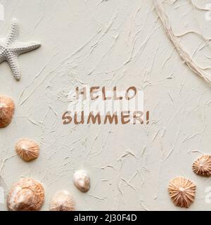 Text Hello Summer. Off white background with starfish, shells, seashells and fisherman net on cream beige off white background. Stock Photo