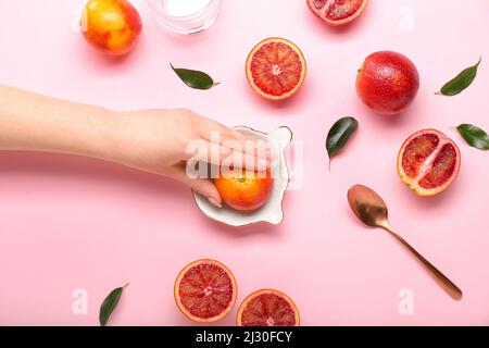 Woman squeezing fresh grapefruit on pink background Stock Photo